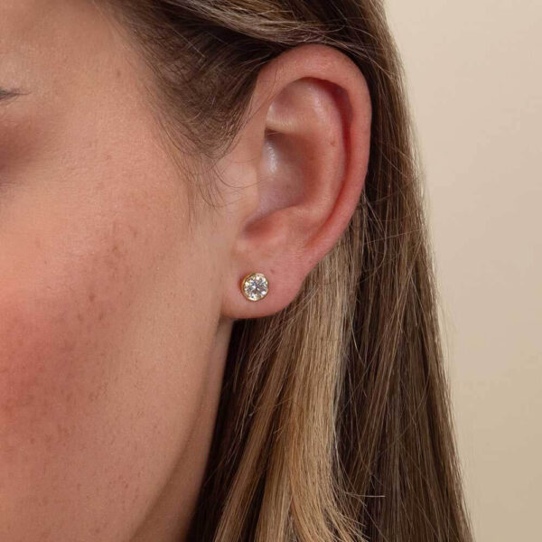 Model Wears Anna 0.50Ct Round Diamond Bezel Stud Earrings Yellow Gold Cropped