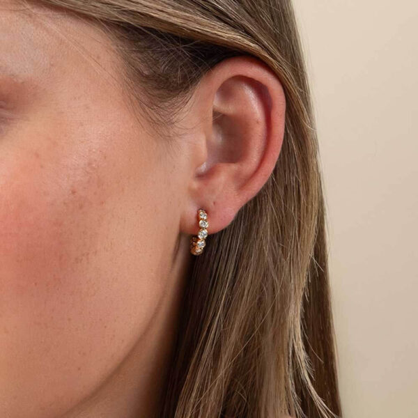 Model Wears Lab Grown Diamond Kira Graduating Bezel Huggie Yellow Gold Earrings Cropped