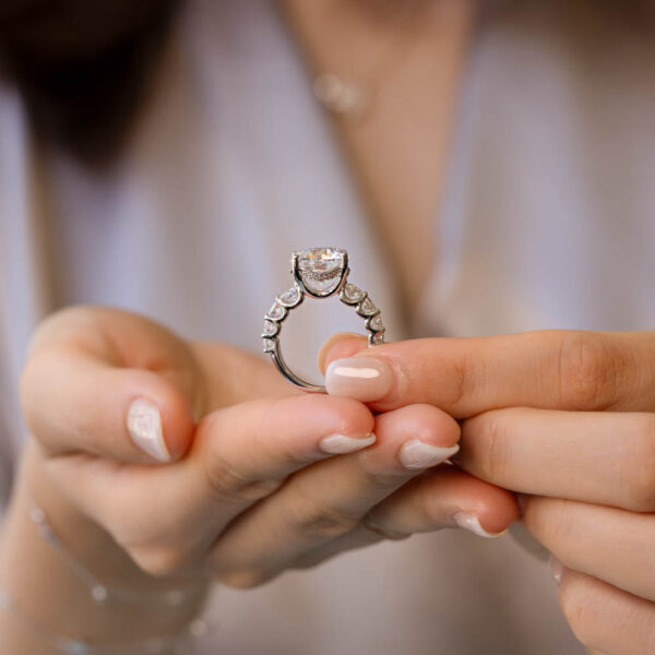 Model Wears Maxwell White Gold Moissanite Round Under Rail Prong Set Scallop Graduating Band Ring