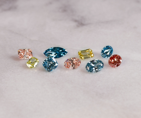 Scattered Loose Pink Yellow And Blue Lab Grown Diamonds On Marble